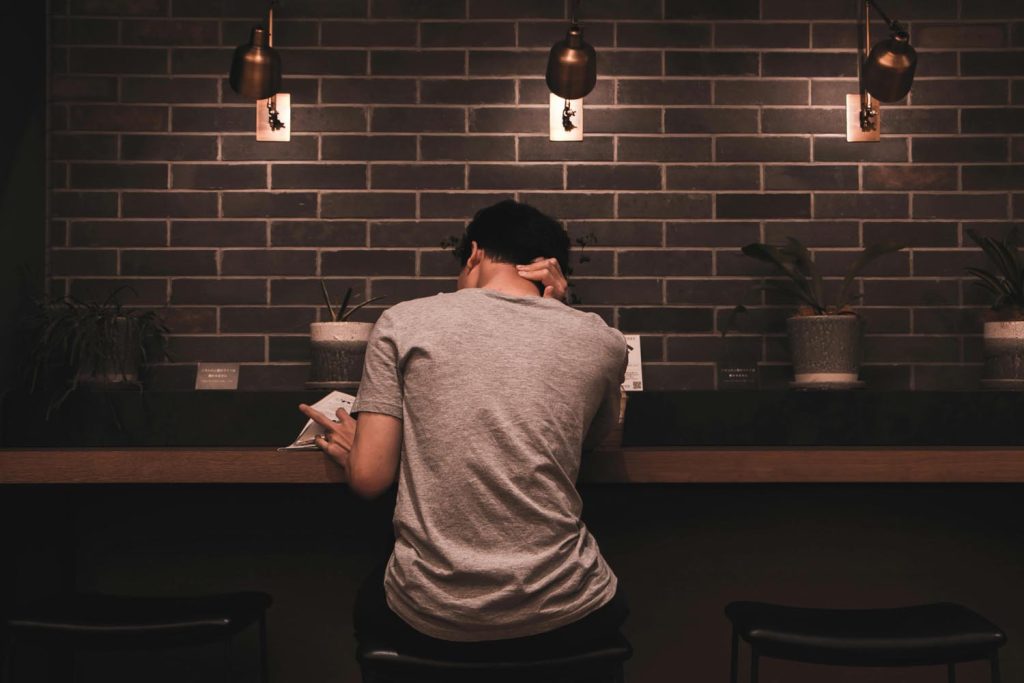 Man next to his backpack writing while listing to music at a coffee shop in Washington, DC