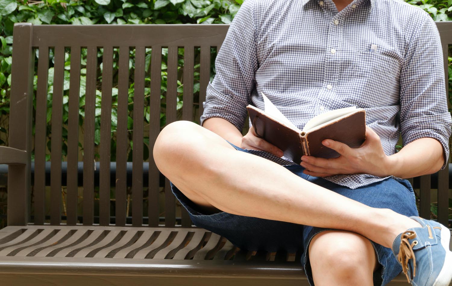 Man in park reading about vulnerability and masculinity, alongside two men embracing with a firm back pat, symbolizing emotional connection and vulnerability in Maryland and DC.