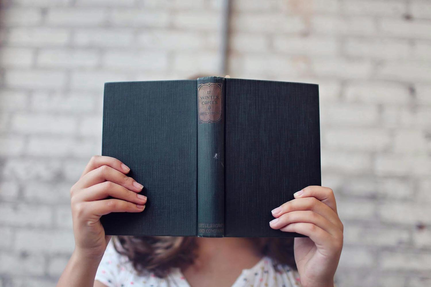 A person reading a blue book about belonging, symbolizing emotional connection and personal history in Maryland and DC.