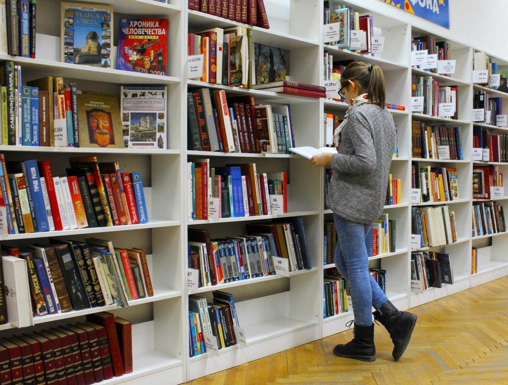 A parent with hobbies searching for the perfect book in a messy library, symbolizing defiance and emotional reflection in Maryland and DC.