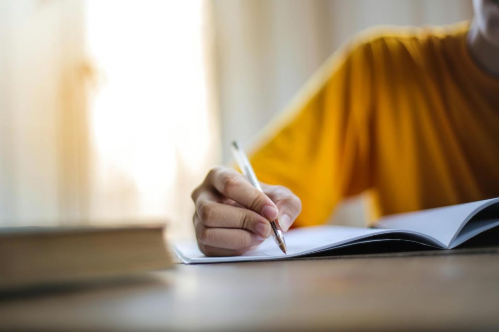 A woman studying new words like Troglodyte in French indoors while rain pours outside, symbolizing joy and emotional connection in Maryland and DC.