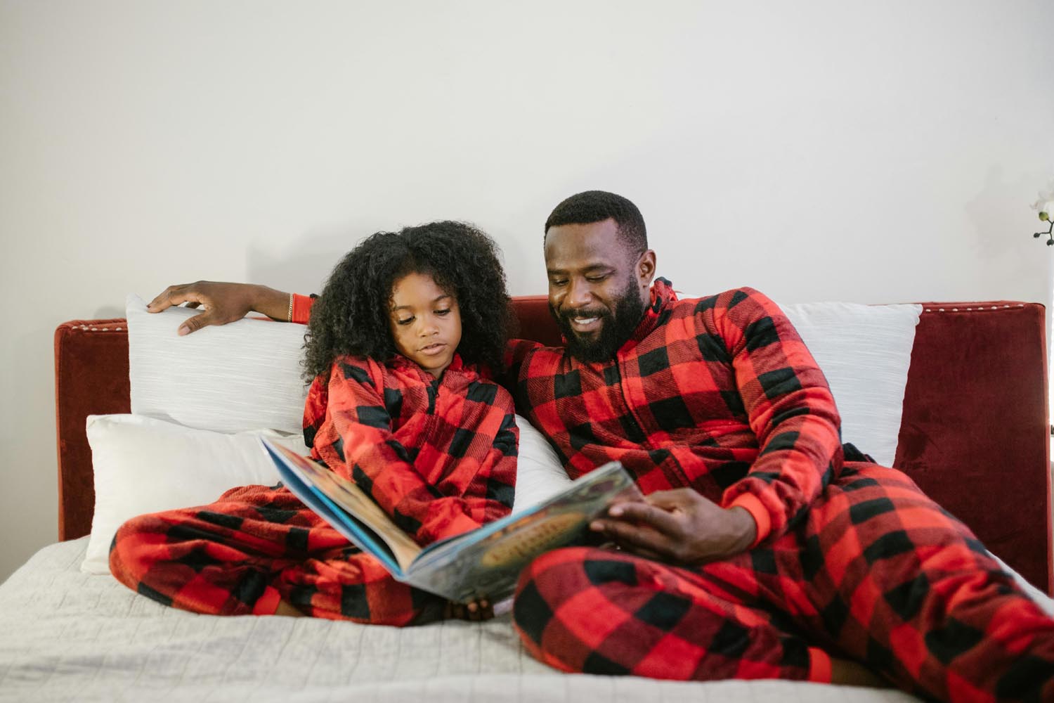 A parent and child reading while snowed in at Kwanzaa holiday in their pajama after going home for the holidays with the goal to teach the alphabet, symbolizing protection, emotional transitions and connection in Maryland and DC.