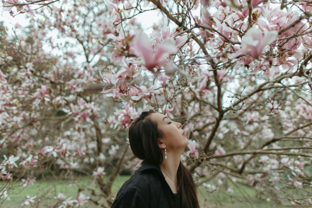 Woman being present observing a fly resting on a tree with spring sunlight streaming in, breathing in the bloom scent, symbolizing unexpected connection and emotional reflection in Maryland and DC.