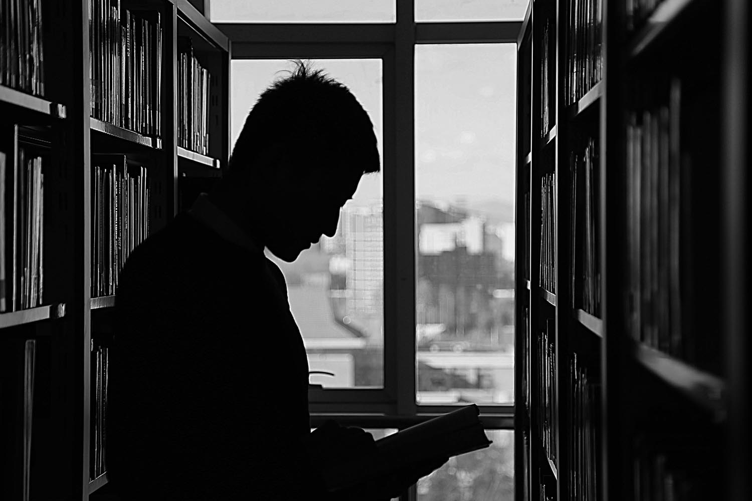 A man in the city reading about practicing compassion and protection for the homeless, symbolizing emotional growth and loss of adult identity in Maryland and DC.